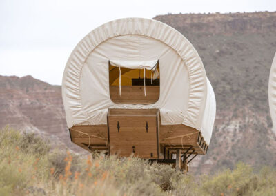 Covered wagon-style glamping accommodation in desert.