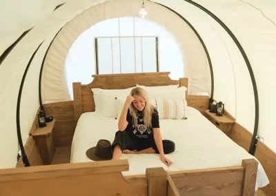 Woman sitting in cozy curved ceiling bedroom.