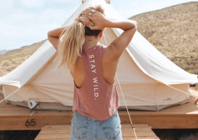 Woman near glamping tent with "Stay Wild" shirt.