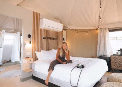 Woman relaxing in cozy glamping tent with stylish decor.